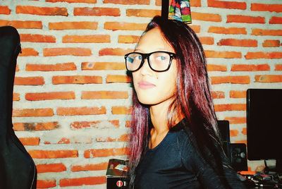 Portrait of woman against brick wall