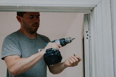 A young man with a drill in his hands.