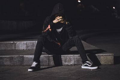 Full length of man using mobile phone while sitting in city