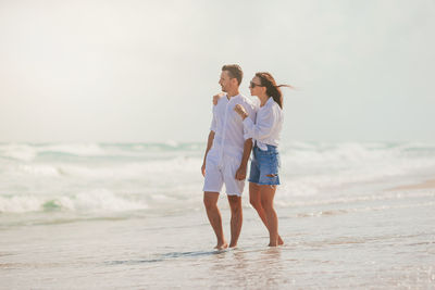 Rear view of couple standing at beach