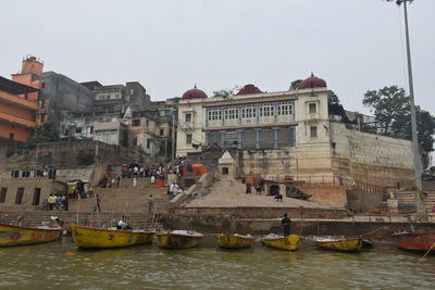 Boats in river against buildings in city