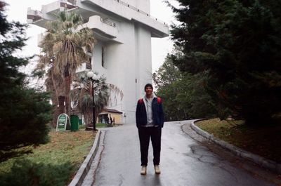 Man standing on footpath by road