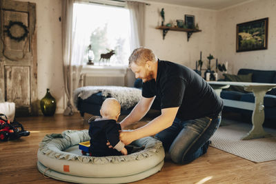 Father carrying son sitting in baby seat at home