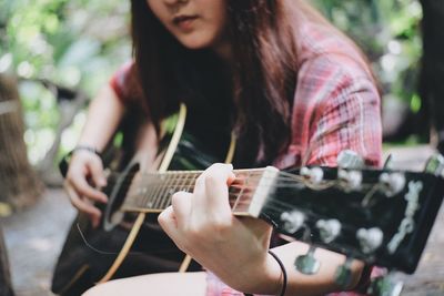 Midsection of woman playing guitar