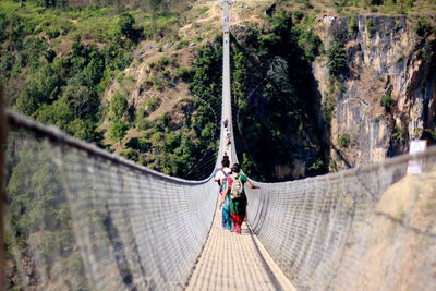 People on footbridge against trees in forest