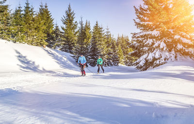 Friends snowboarding on snowcapped field during winter