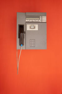 Close-up of telephone booth against red wall
