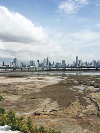 City at waterfront against cloudy sky