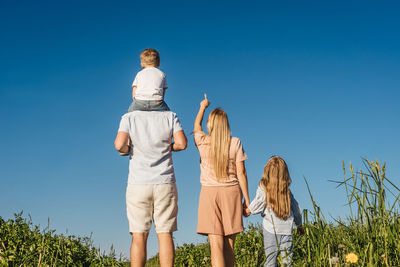 Rear view of friends standing against clear sky