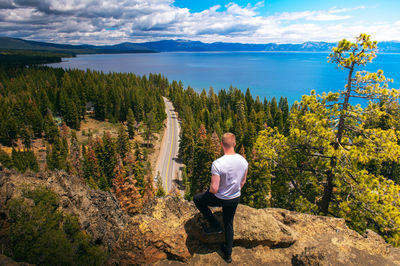 Rear view of woman standing by lake against sky