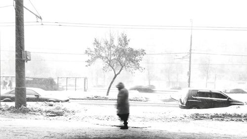 Rear view of man walking on snow covered road