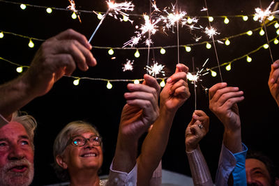 Low angle view of people holding illuminated sparklers