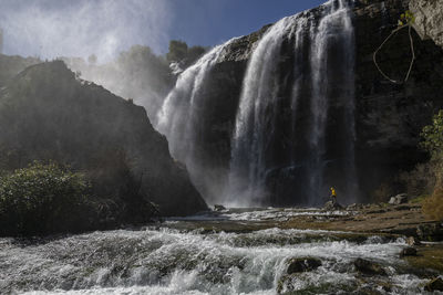 Man standing against waterfall