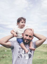 Portrait of man with daughter against sky
