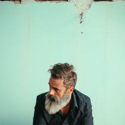 Portrait of man looking away against wall
