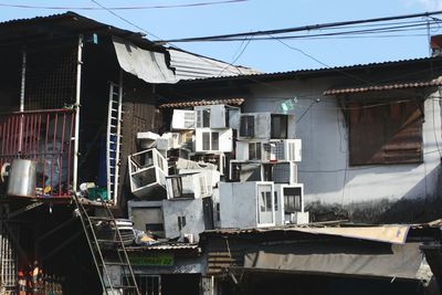 Stack of abandoned air conditioners on roof against clear sky during sunny day