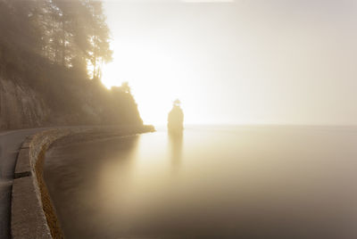 Silhouette man standing by sea against sky