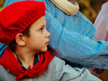 Close-up of boy wearing red hat looking away while sitting with parents