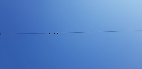 Low angle view of power lines against clear blue sky