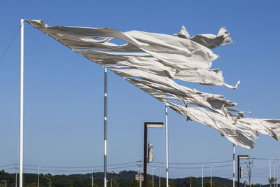 Low angle view of flags waving against clear blue sky