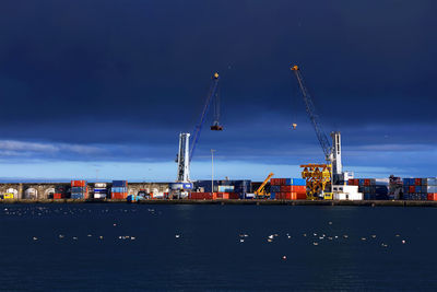 Commercial dock by sea against blue sky