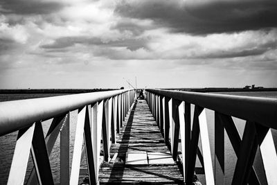 Footbridge over sea against sky