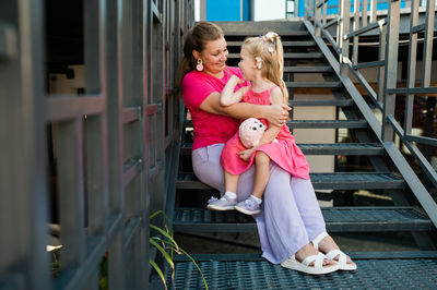 Portrait of young woman sitting on railing