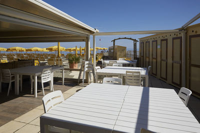 Empty chairs and tables against clear sky