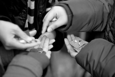 Cropped hands of vendor selling earrings to customer at store