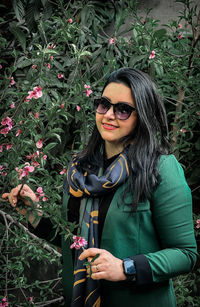 Portrait of young woman standing against plants