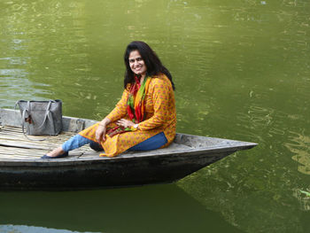 Portrait of smiling young woman sitting on lake