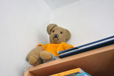 Low angle view of teddy bear on table against wall