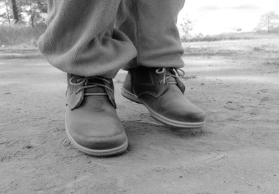 Low section of man wearing shoes on sand