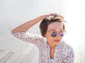 Wind ruffles short hair of freckled woman in colorful sunglasses. smiling woman at urban park. 