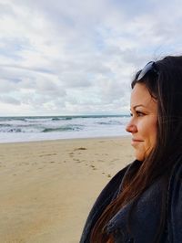 Smiling young woman looking at sea against sky