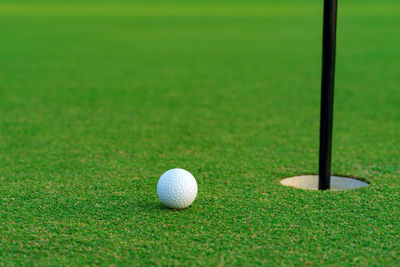 Golf ball on lip of cup at golf court.