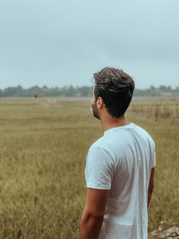 Rear view of young man standing on field