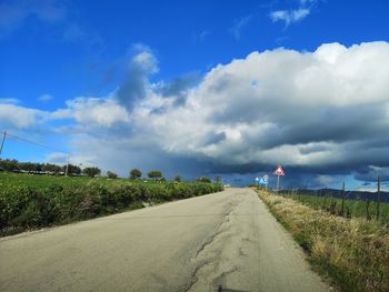 Road amidst field against sky