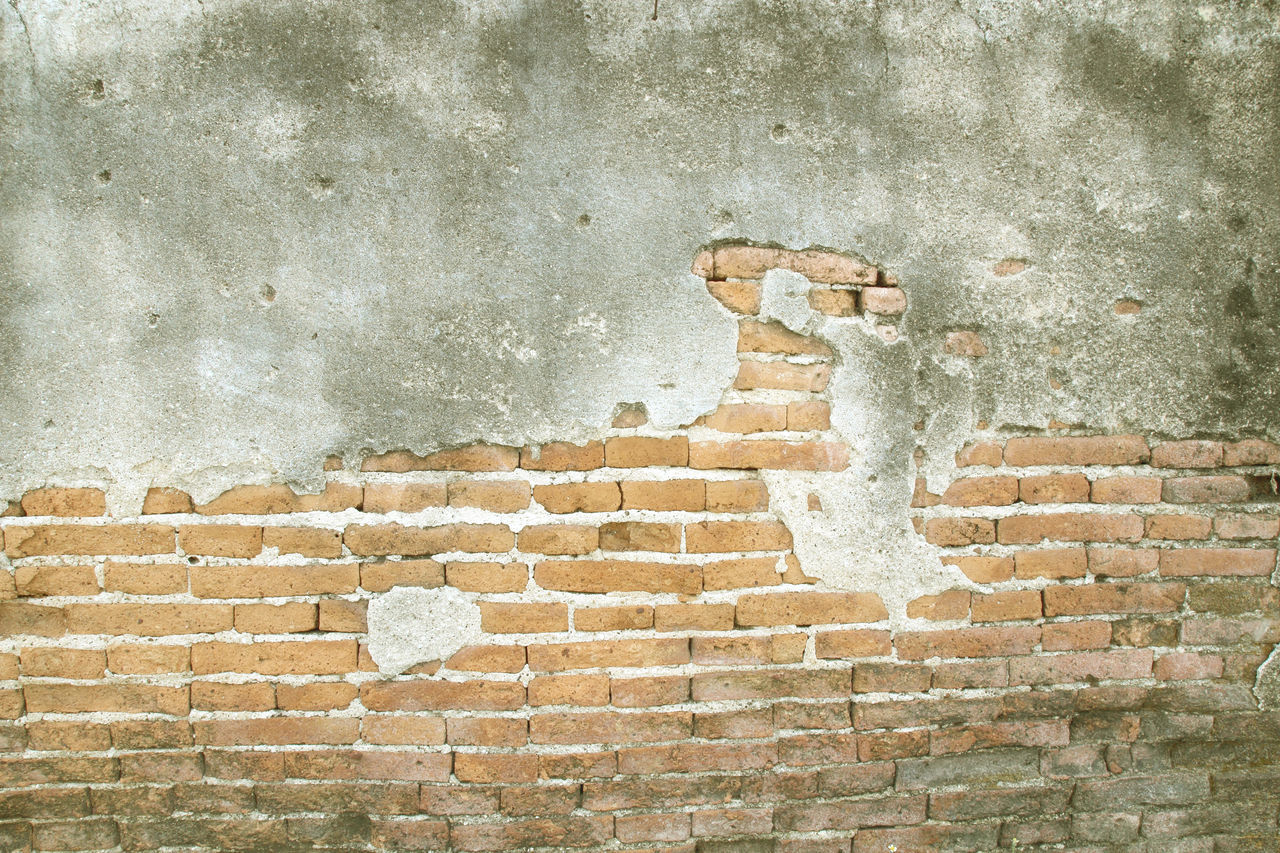 VIEW OF BRICK WALL WITH WEATHERED BUILDING