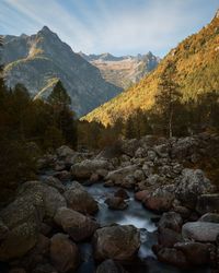 Scenic view of stream by rocks against sky