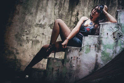 Young woman sitting on staircase of abandoned house