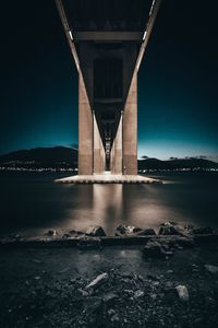 Low angle view of bridge over river against sky at night