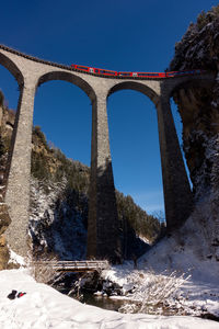 Low angle view of bridge over river against sky during winter