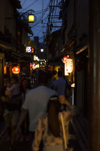People on street against illuminated buildings in city at night