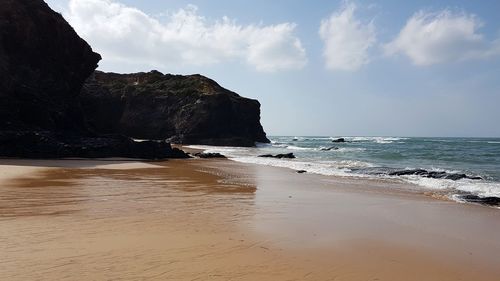 Rock formation on beach against sky