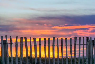 Fence on landscape against romantic sky at sunset