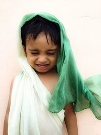 Boy head covered with scarf crying against white background