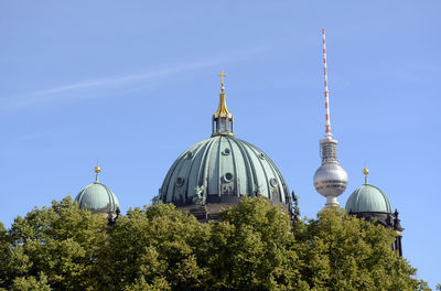 Low angle view of fernsehturm and berlin cathedral by trees against sky