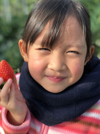 Close-up portrait of cute girl holding strawberry