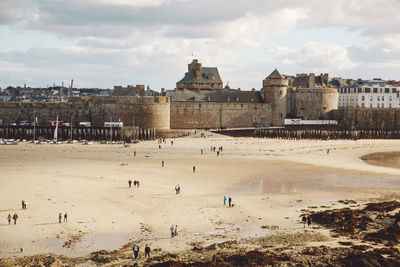 People at beach against historic buildings in city